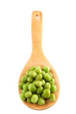 Green peas on wooden spoon over white backgroundの写真素材