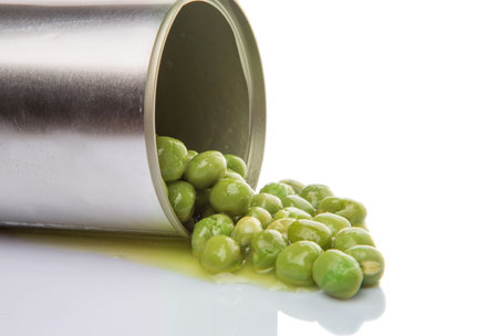 Green peas in a tin can over white background