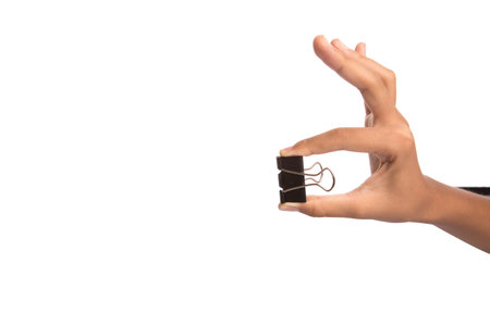 Female hand holding binder clip over white backgroundの写真素材