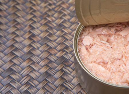 Pieces of tuna fish in a can over wicker backgroundの写真素材