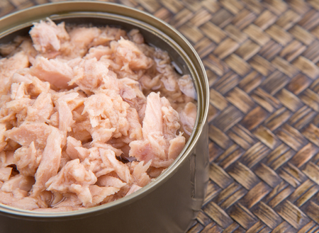 Pieces of tuna fish in a can over wicker backgroundの写真素材