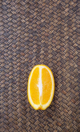 Slice of orange fruit over wicker background の写真素材