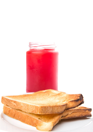 A bottle of strawberry jam and bread toast on a plate over white backgroundの写真素材