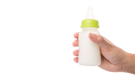 Female hand holding a baby bottle of milk over white backgroundの写真素材