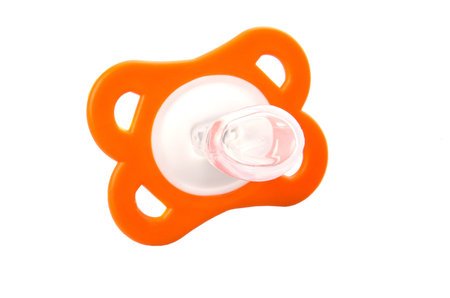 Orange colored pacifier over white background