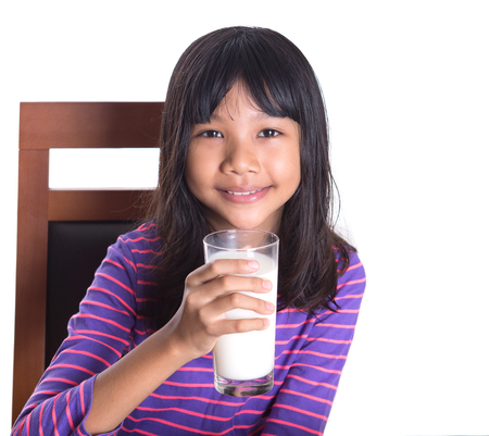 Young Asian girl with a glass of milk over white backgroundの写真素材