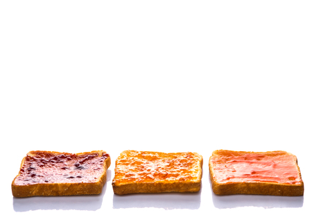 Mix fruit, blueberry, orange fruit jam spread on bread toast over white backgroundの写真素材