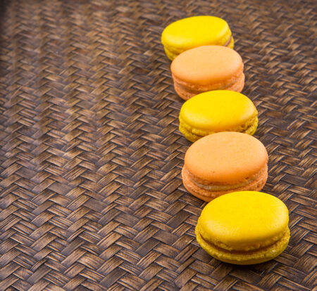 Yellow and orange colored French macarons on wicker backgroundの写真素材