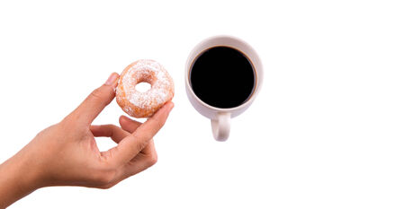 Female hand holding doughnuts with a mug of coffee over white backgroundの写真素材