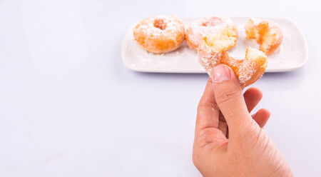 Female hand holding doughnuts over white backgroundの写真素材