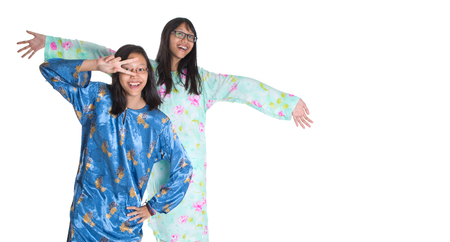 Malay teenage sisters in traditional attire over white backgroundの写真素材