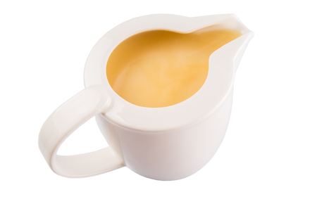 Condensed milk in a small milk jug over white backgroundの写真素材