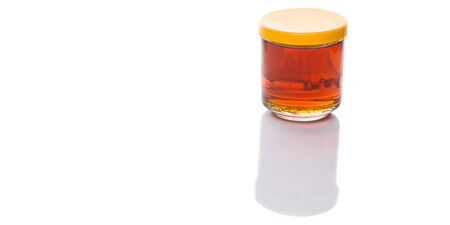 Honey in glass jar over white backgroundの写真素材