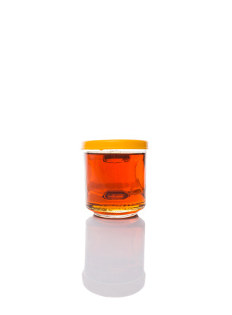 Honey in glass jar over white backgroundの写真素材
