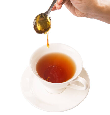 Female hand mixing honey with tea over white backgroundの写真素材
