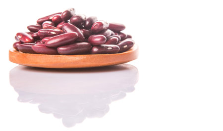 Red kidney beans on wooden spoon over white background