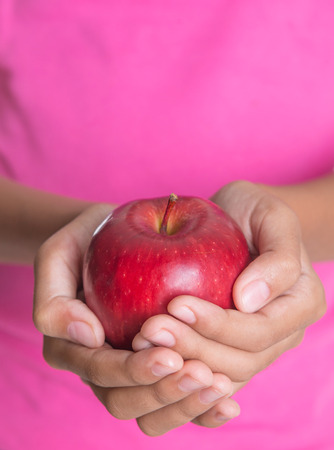 Girl hands holding a red apple over white backgroundの写真素材
