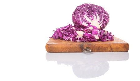 Chopped red cabbage on cutting board over white backgroundの写真素材