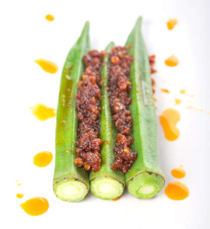 Boiled raw okra or ladies fingers with deep fried crunched chili sambal over white backgroundの写真素材