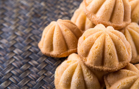 Kuih bahulu, a Malay sweet egg sponge cake on wicker mat.