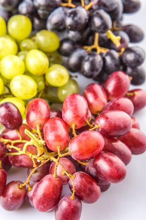 Red, green and black grapes fruits over white backgroundの写真素材