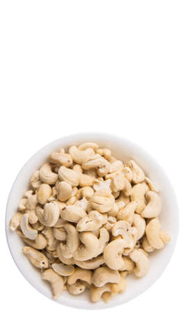 Raw cashew nuts in a white bowl over white backgroundの写真素材