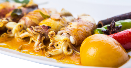 Delicious fried squid with curry gravy on white plateの写真素材