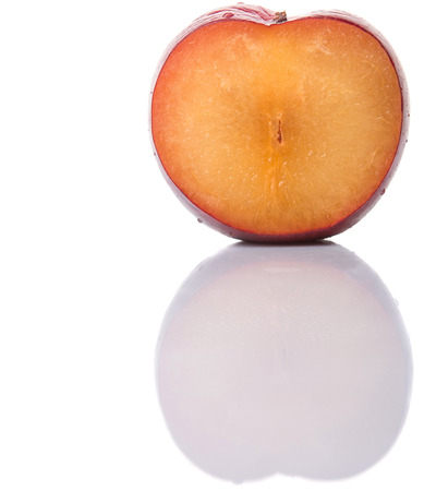 A slice of victoria plum or red plum over white backgroundの写真素材