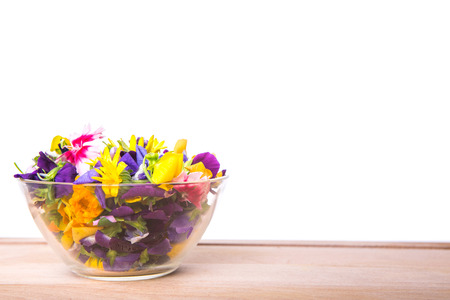 Mix edible flower salad in a glass bowl on wooden cutting boardの写真素材