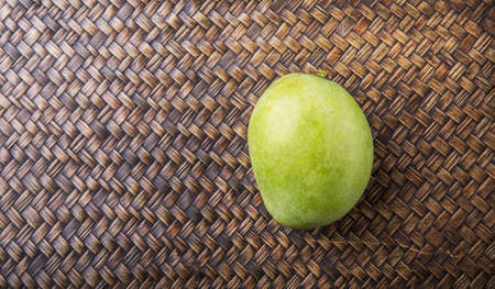 Green mango over wicker backgroundの写真素材
