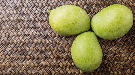 Green mango over wicker backgroundの写真素材