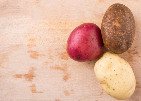Red brown yellow potatoes on wooden surfaceの写真素材