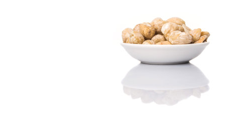 Candlenut seed in white bowl over white background
