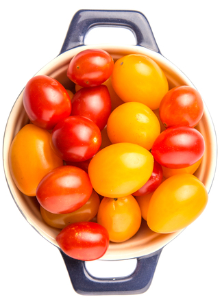 Yellow and red grape tomato in a blue pot over white backgroundの写真素材
