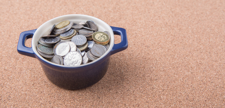 Malaysian coins in a blue pot on cork board surfaceの写真素材
