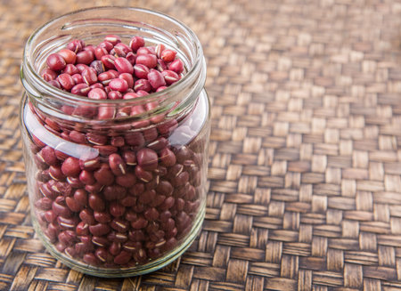 Red adzuki beans in a mason jar over wicker background