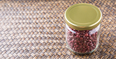 Red adzuki beans in a mason jar over wicker background