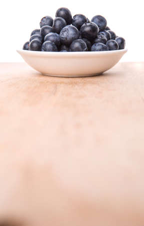 Blueberry fruits in a white bowl on wooden board backgroundの写真素材