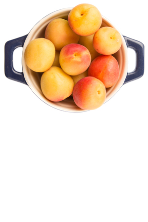 Ripe apricot fruits in a bliue pot over white backgroundの写真素材