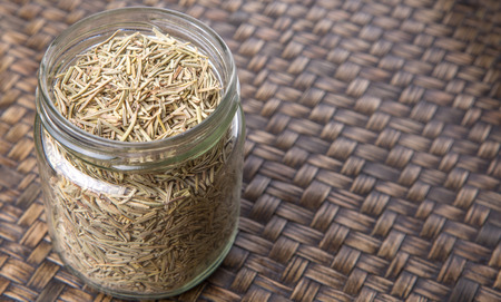 Dried rosemary herb in a mason jar on wicker backgroundの写真素材