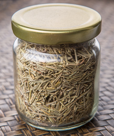 Dried rosemary herb in a mason jar on wicker backgroundの写真素材