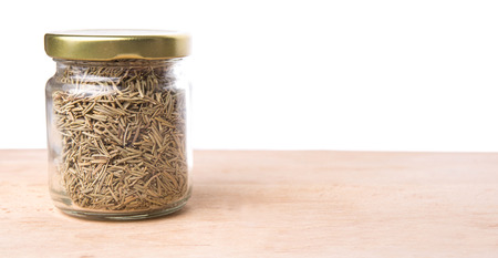 Dried rosemary herb leaves in a mason jar on wooden boardの写真素材