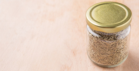 Dried rosemary herb leaves in a mason jar on wooden boardの写真素材