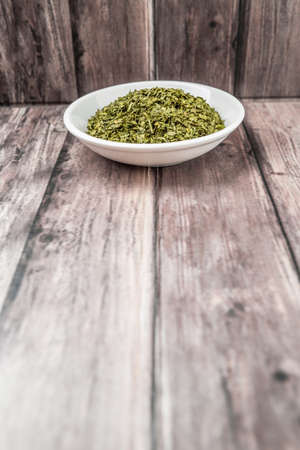 Dried parsley herb in white bowl on weathered wooden backgroundの写真素材