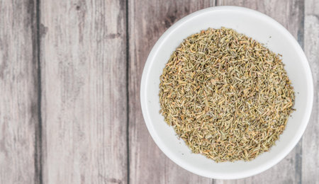 Dried thyme herbs in white bowl over weathered wooden backgroundの写真素材