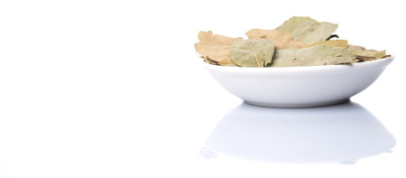 Dried bay leaves in white bowl over white backgroundの写真素材