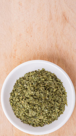Dried parsley herb in white bowl over wooden backgroundの写真素材