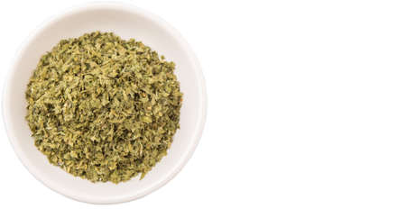 Dried parsley herbs in white bowl over white backgroundの写真素材