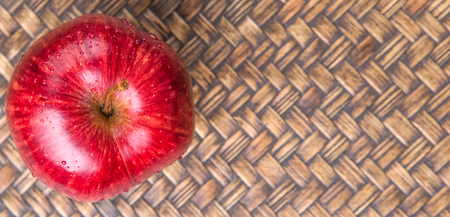 Red apple over wicker backgroundの写真素材