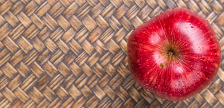 Red apple over wicker backgroundの写真素材